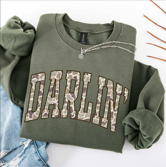 Folded olive green Darlin’ sweatshirt with camo block lettering
Cozy country style sweatshirt with camo graphic letters
Rustic western sweatshirt folded with jewelry and jeans
Olive green Darlin’ pullover for cowgirl country outfit