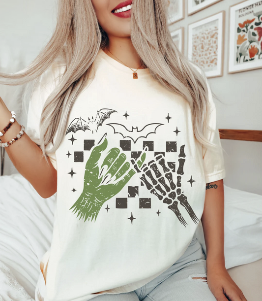 Woman wearing beige Halloween pinky promise t-shirt with zombie and skeleton hands
Spooky season tee with bats, checkerboard, and creepy cute design
 Casual Halloween graphic t-shirt for fall outfits and parties