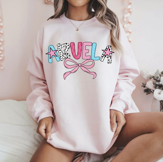 Abuela graphic sweatshirt with colorful lettering and pink bow design on light pink pullover
