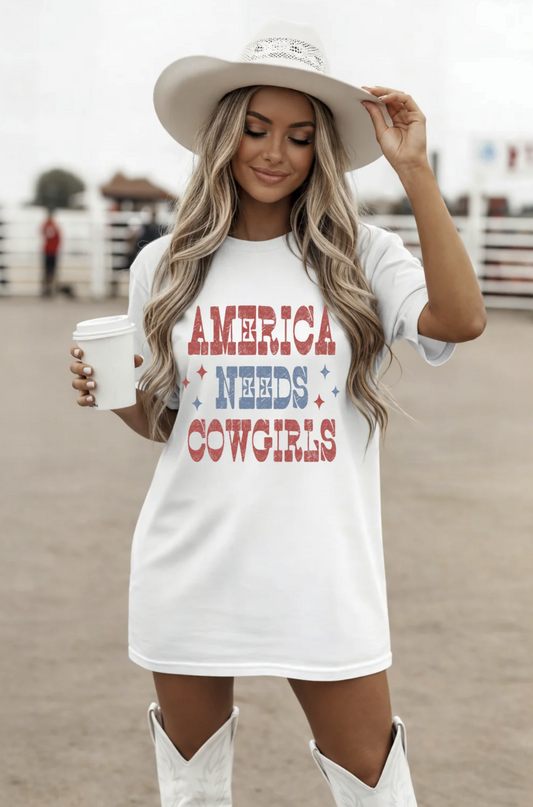 White t-shirt with red white and blue text reading “America Needs Cowgirls” worn with cowboy hat and boots