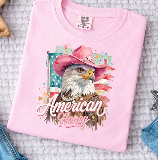 Pink Comfort Colors t-shirt featuring eagle with pink cowboy hat and “American Honey” patriotic graphic