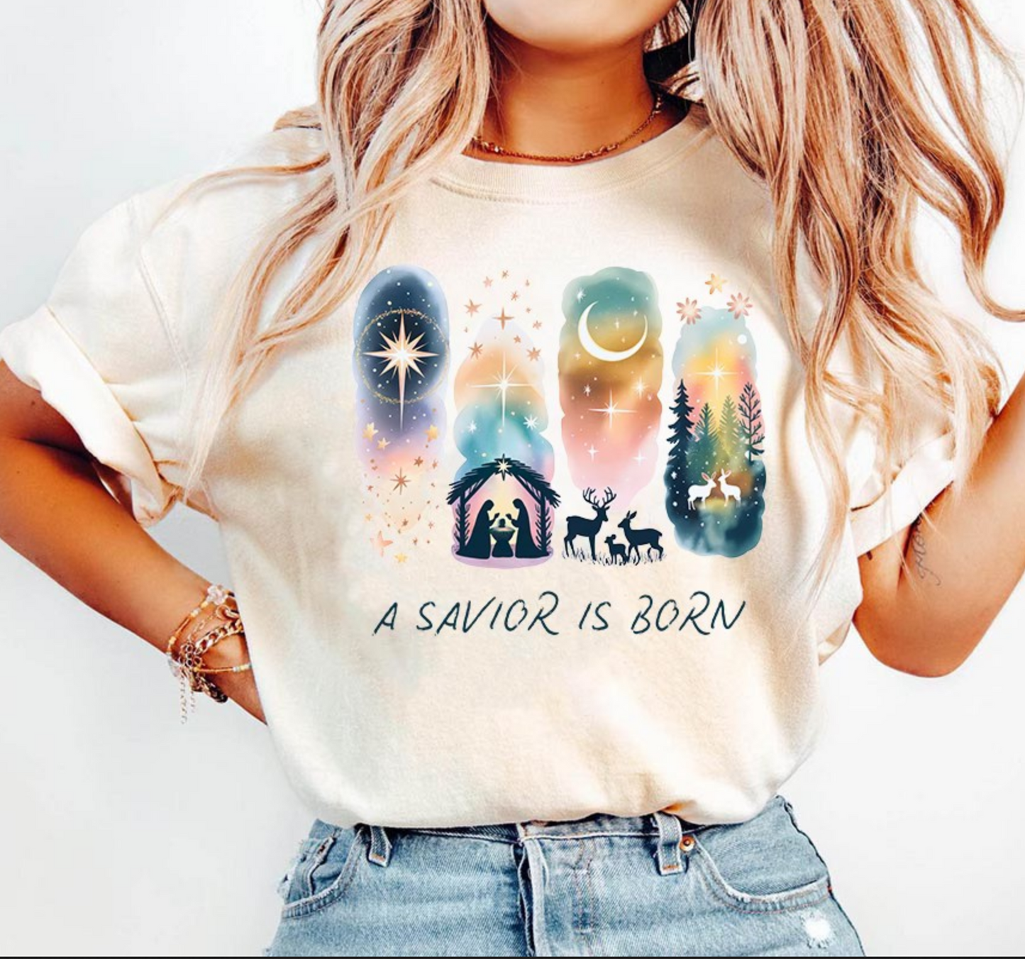 Beige t-shirt with watercolor nativity design and the words A Savior Is Born.

Watercolor Christmas nativity tee featuring holy family and star of Bethlehem.

Christian holiday shirt with peaceful night sky and nativity silhouettes.

Woman wearing faith-based Christmas nativity graphic tee.