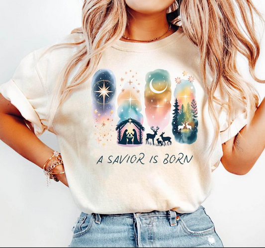 Beige t-shirt with watercolor nativity design and the words A Savior Is Born.

Watercolor Christmas nativity tee featuring holy family and star of Bethlehem.

Christian holiday shirt with peaceful night sky and nativity silhouettes.

Woman wearing faith-based Christmas nativity graphic tee.