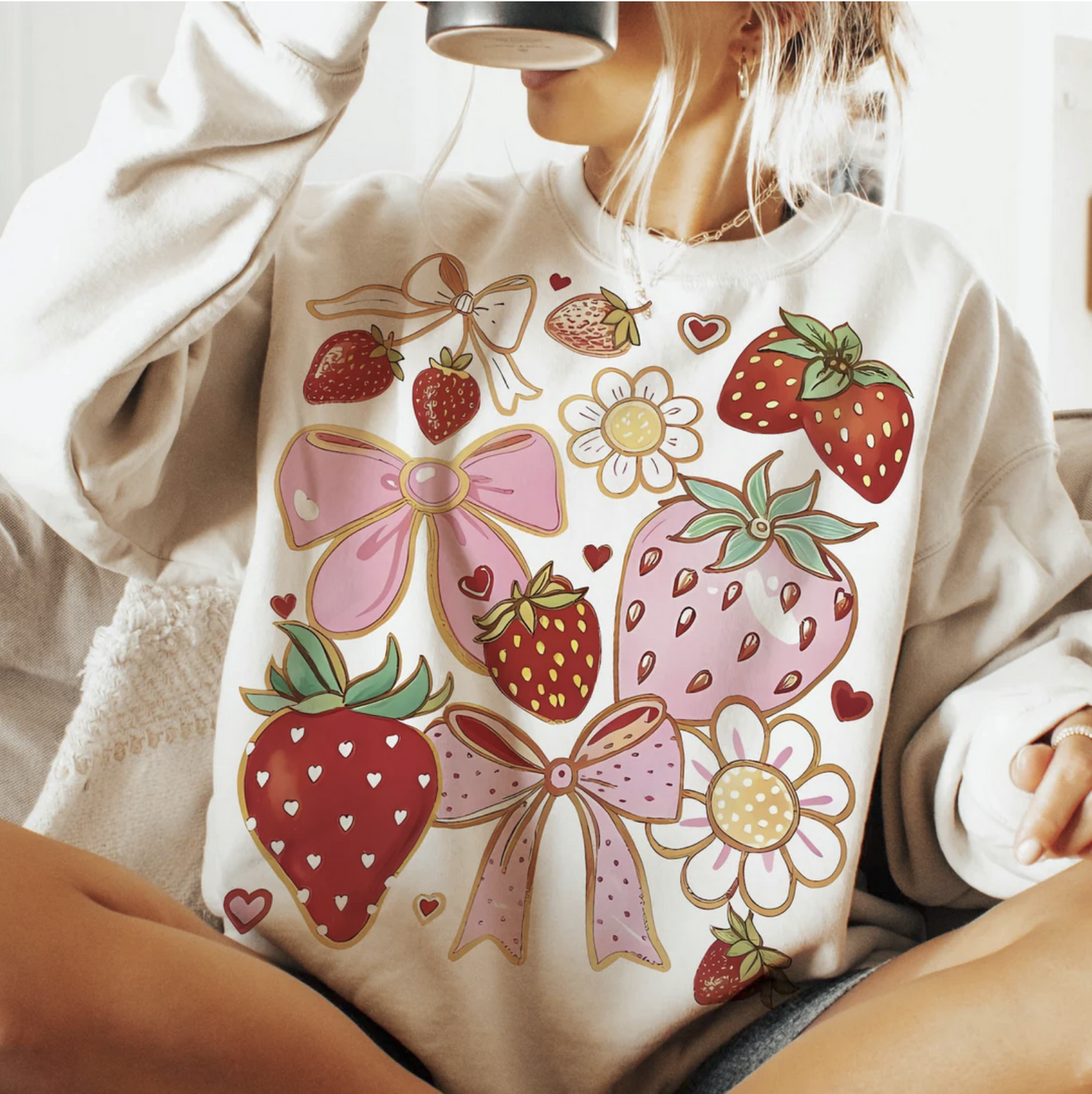 Strawberries and bows graphic sweatshirt with pastel pink and red fruit and floral designs on beige pullover
