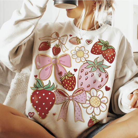 Strawberries and bows graphic sweatshirt with pastel pink and red fruit and floral designs on beige pullover
