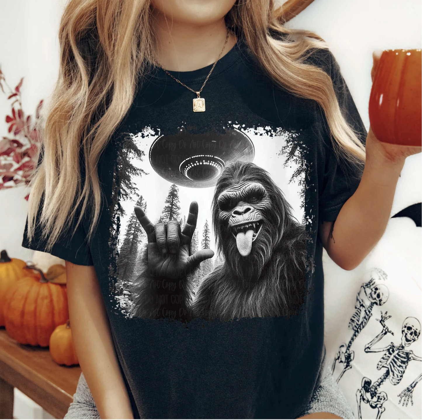 Bigfoot UFO Rock On graphic tee with Sasquatch throwing rock hand under flying saucer on black shirt
