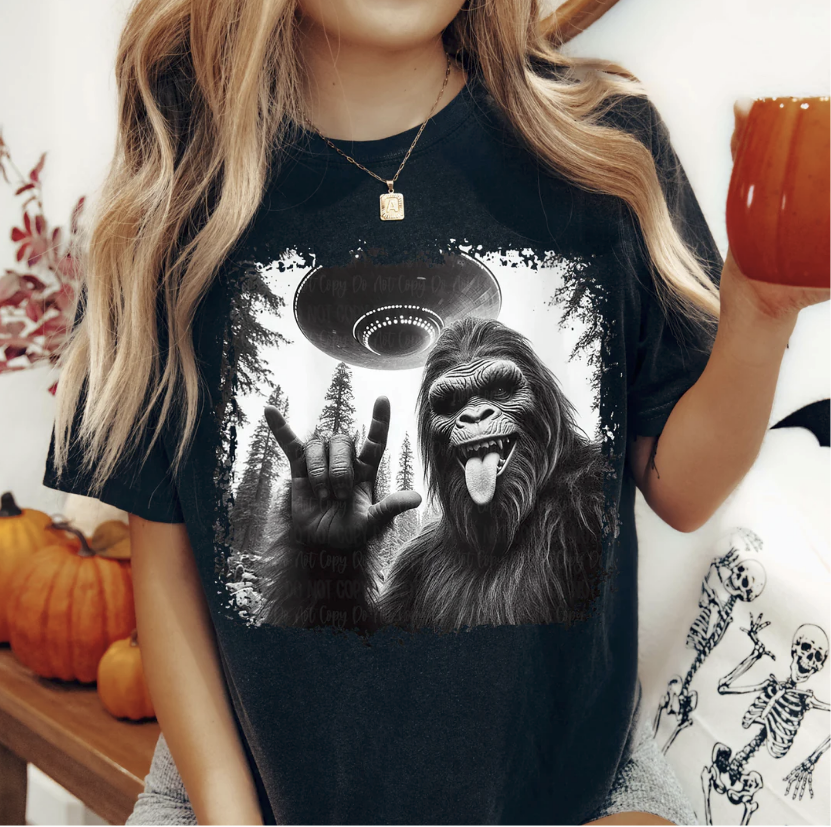 Bigfoot UFO Rock On graphic tee with Sasquatch throwing rock hand under flying saucer on black shirt
