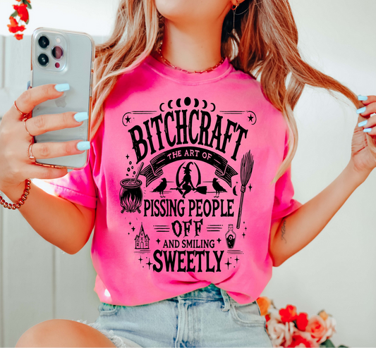 Hot pink Bitchcraft t-shirt with black witchy design and sarcastic text, worn by a woman taking a mirror selfie.