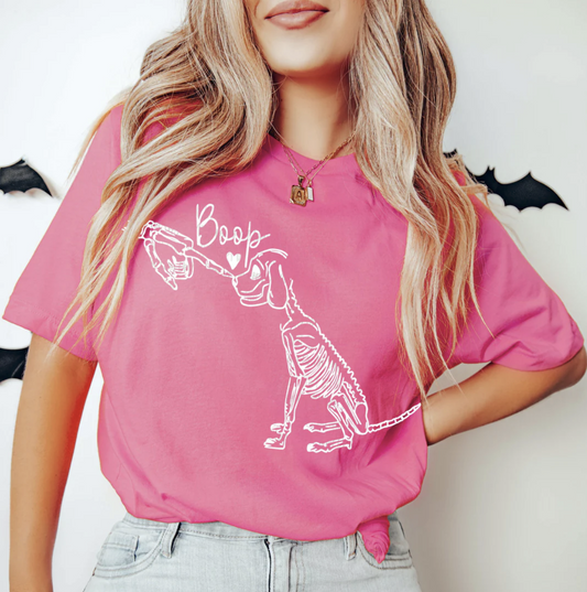 Pink t-shirt with white skeleton dog graphic giving a “boop” with heart – cute spooky Halloween dog lover tee