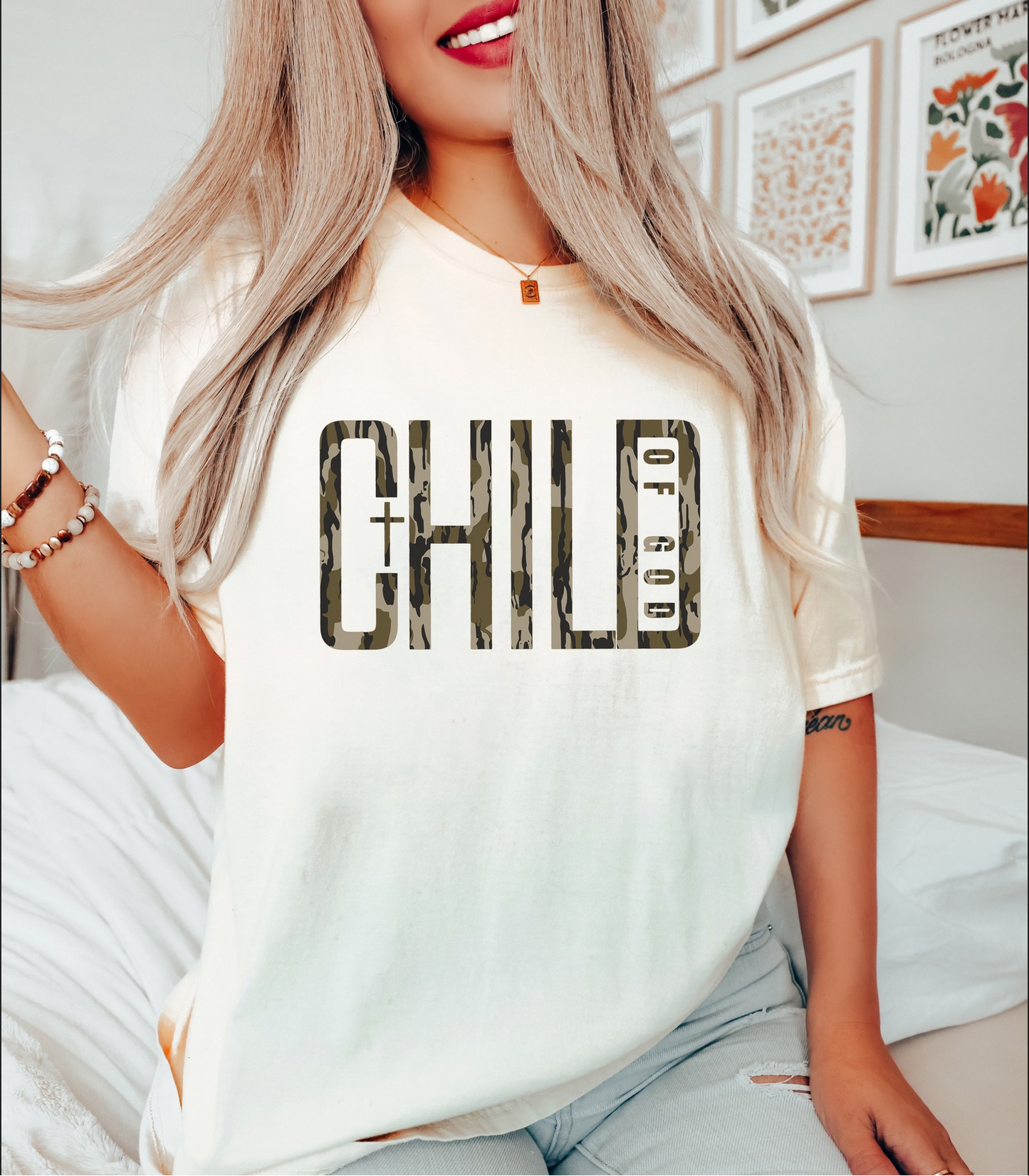 Woman wearing cream “Child of God” t-shirt with camo text and cross design

Christian faith graphic tee with inspirational lettering

Soft unisex “Child of God” shirt styled for everyday wear

Faith-based t-shirt perfect for church or casual outfits