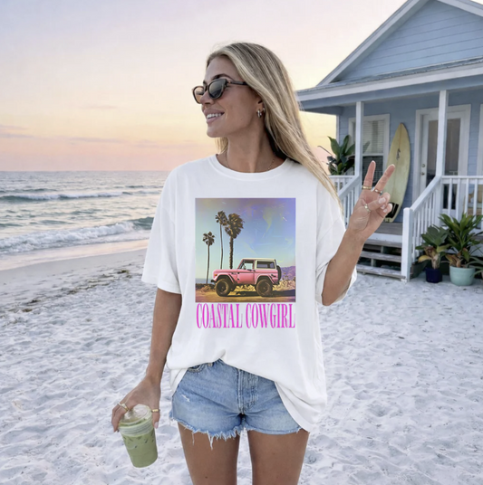 White t-shirt with retro beach scene and pink truck graphic reading “Coastal Cowgirl”