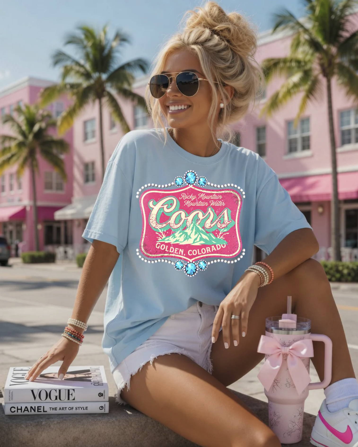 Light blue graphic t-shirt featuring a colorful western mountain-inspired design with a faux rhinestone border on a relaxed-fit unisex tee.