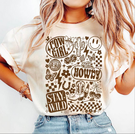 Cream Cowgirl Howdy Stay Wild t-shirt with retro western collage design including boots, cactus, butterflies, and smiley faces, worn by a woman with long blonde hair.