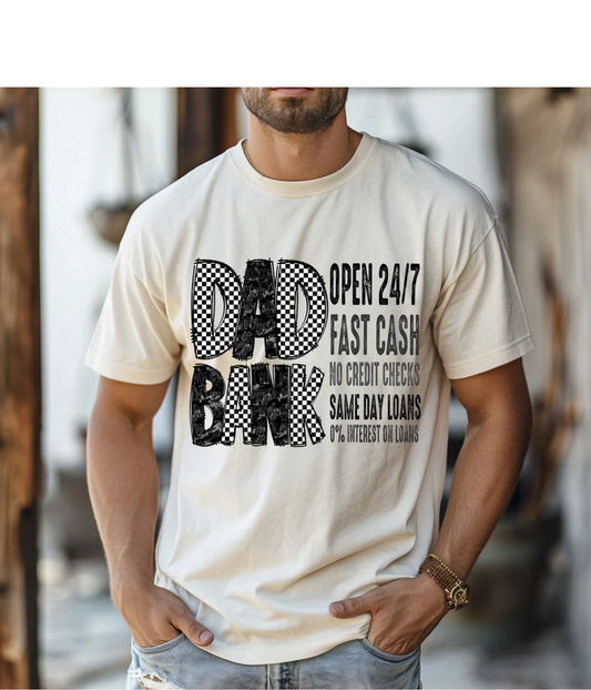 Dad Bank funny graphic tee with bold lettering and retro checkered detail on beige shirt

