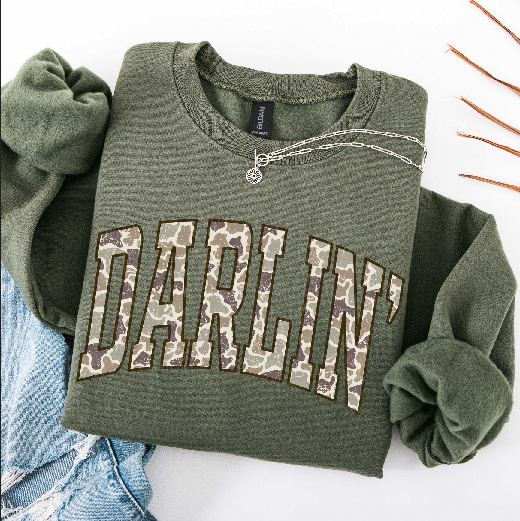 Folded olive green Darlin’ sweatshirt with camo block lettering

Cozy country style sweatshirt with camo graphic letters

Rustic western sweatshirt folded with jewelry and jeans

Olive green Darlin’ pullover for cowgirl country outfit