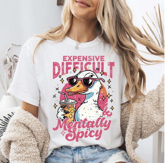 White Expensive Difficult & Mentally Spicy t-shirt with duck graphic in sunglasses holding iced coffee, worn by a woman in cozy casual style.