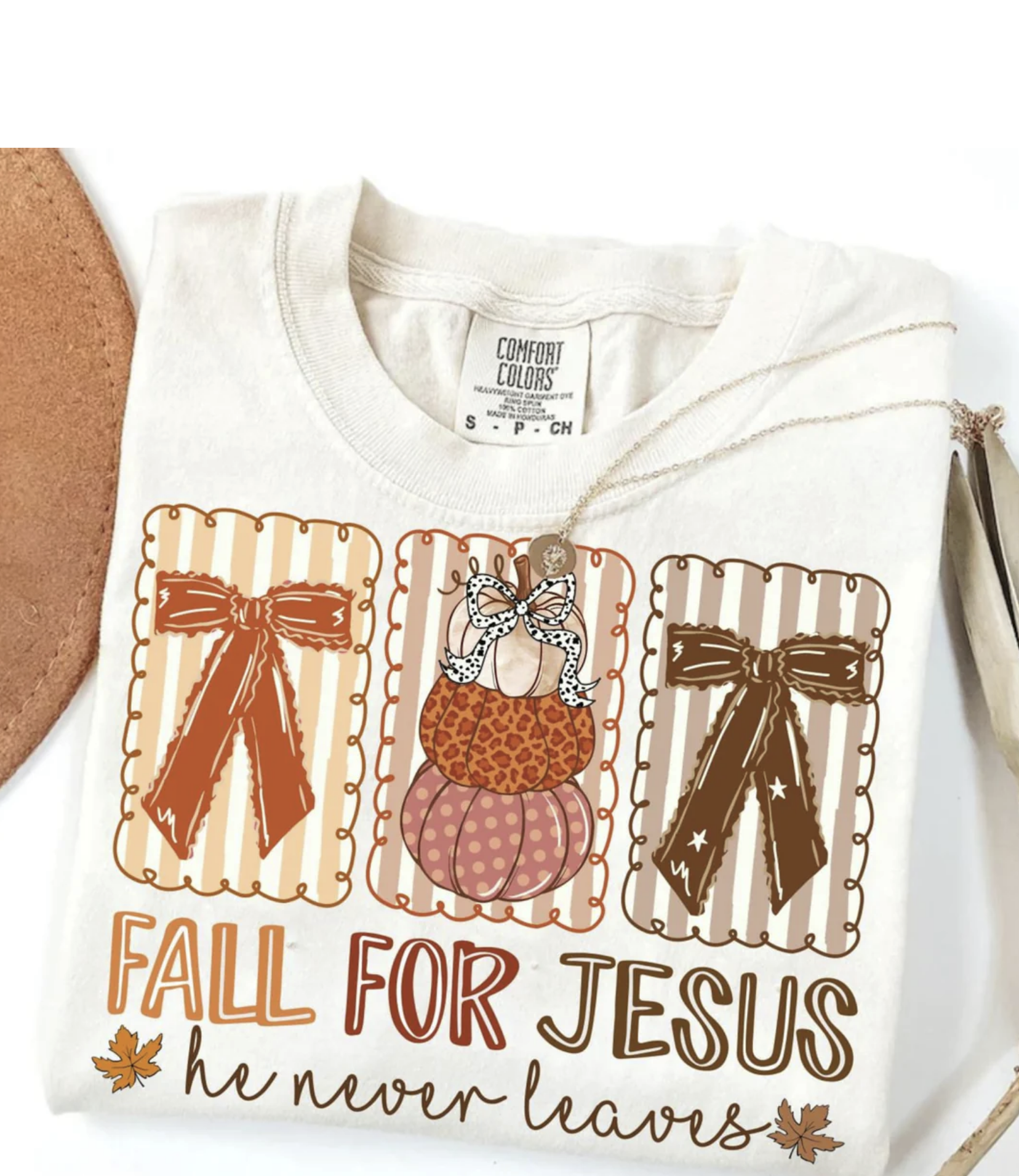 Cream Comfort Colors t-shirt with “Fall for Jesus He Never Leaves” design featuring pumpkins, bows, and autumn colors