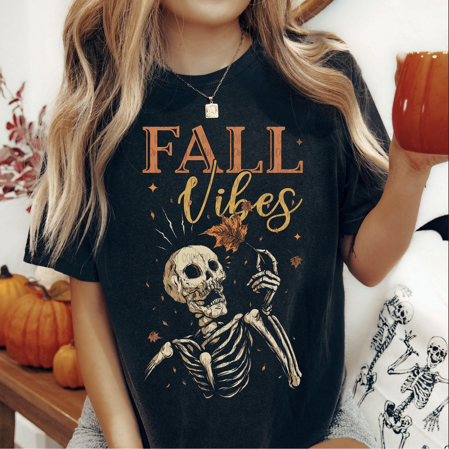 Black tee with skeleton holding a leaf, text “Fall Vibes.”

Woman wearing Fall Vibes skeleton shirt styled with pumpkins and fall décor.