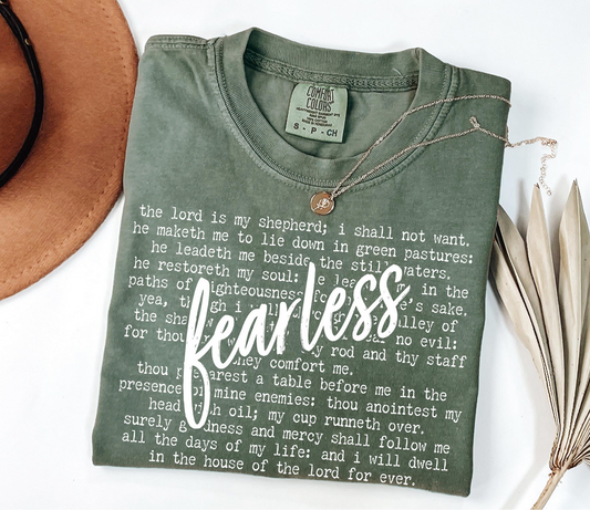 Olive green Fearless Psalm 23 t-shirt with white scripture lettering and bold “Fearless” text overlay, laid flat with accessories.