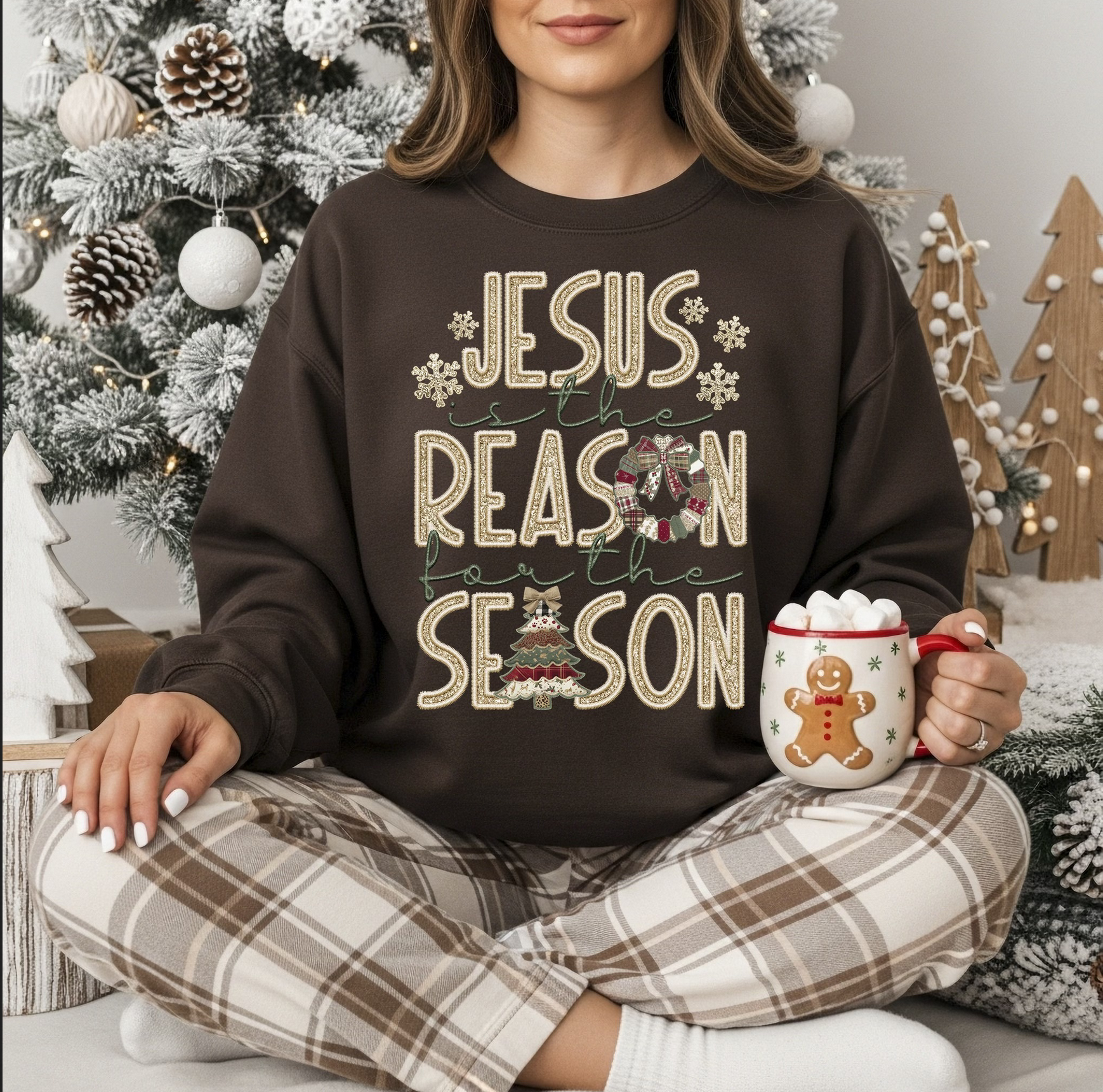 "Brown Christmas sweatshirt with Jesus Is the Reason for the Season lettering and snowflakes in a cozy winter setting."