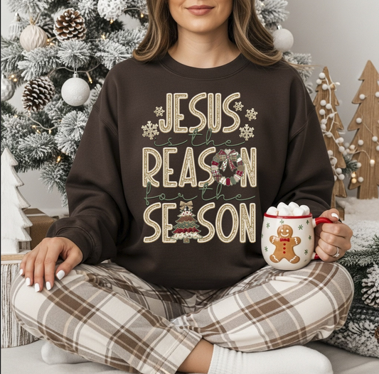 "Brown Christmas sweatshirt with Jesus Is the Reason for the Season lettering and snowflakes in a cozy winter setting."