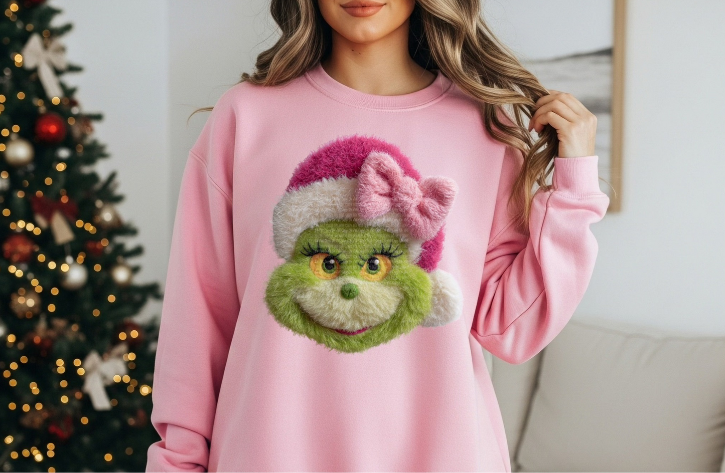 Pink sweatshirt with cute fuzzy green holiday creature wearing a pink Santa hat and bow.