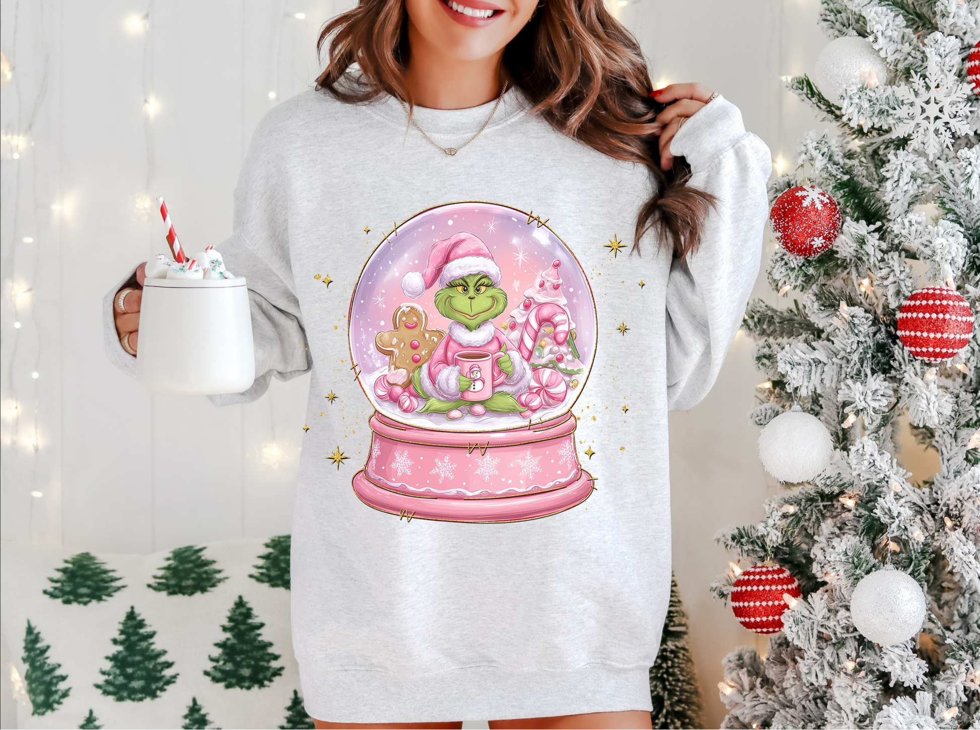 Gray sweatshirt with pink snow globe and cute green holiday creature design.

Christmas snow globe sweatshirt featuring festive pastel artwork.

Cozy winter crewneck with green creature inside pink holiday globe.

Woman wearing cute holiday snow globe sweater beside Christmas tree.