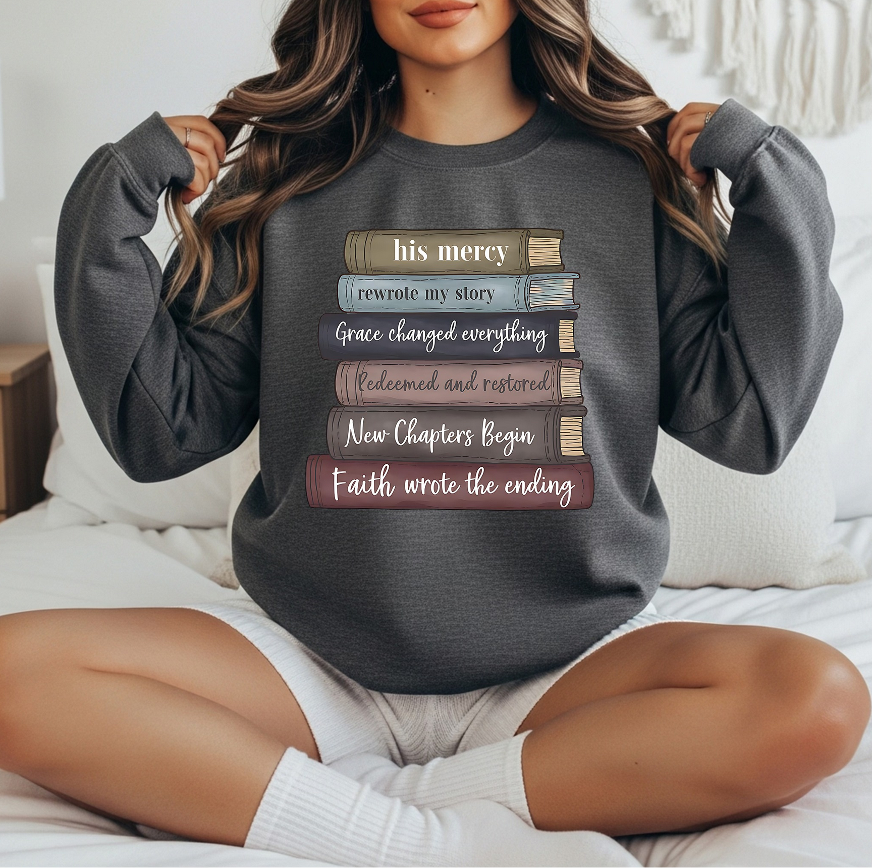 Dark gray sweatshirt with stacked books graphic featuring inspirational Christian quotes and faith-themed lettering.