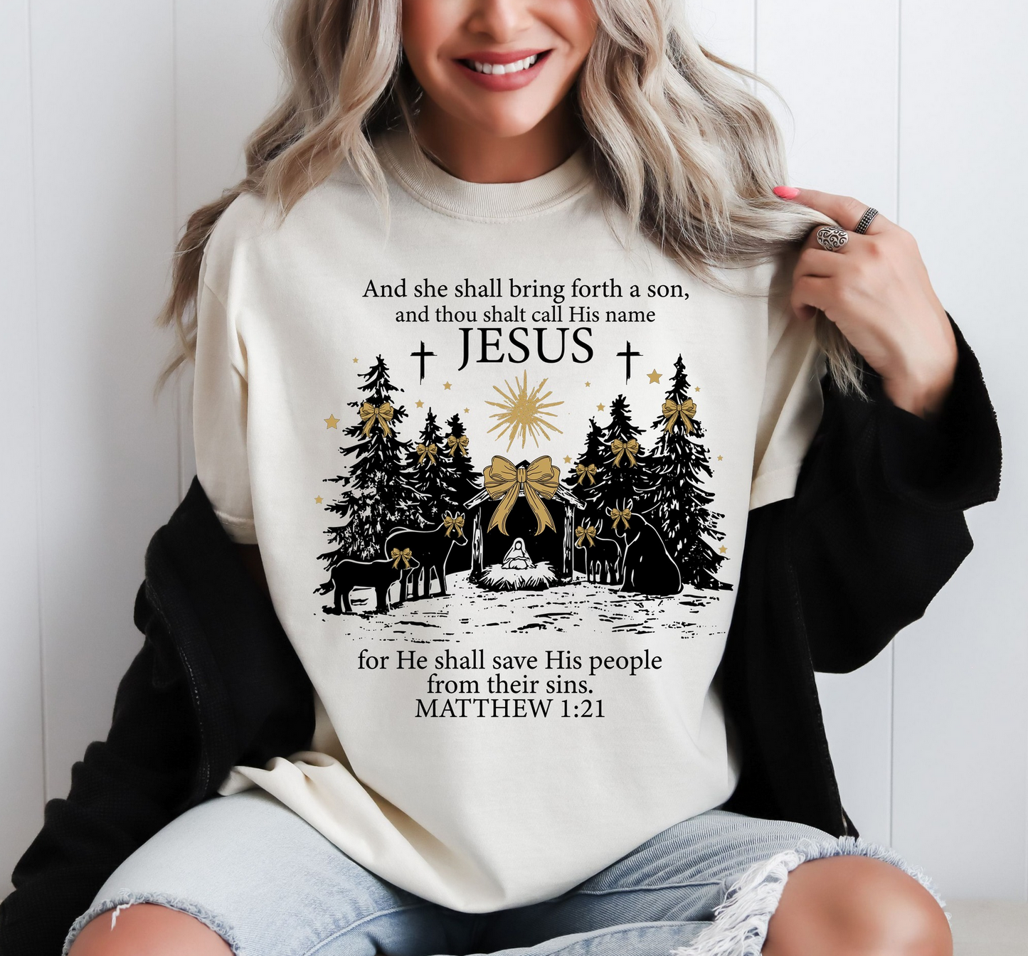 Cream sweatshirt with nativity scene, trees, star, and Matthew 1:21 Bible verse with Jesus’ name highlighted.