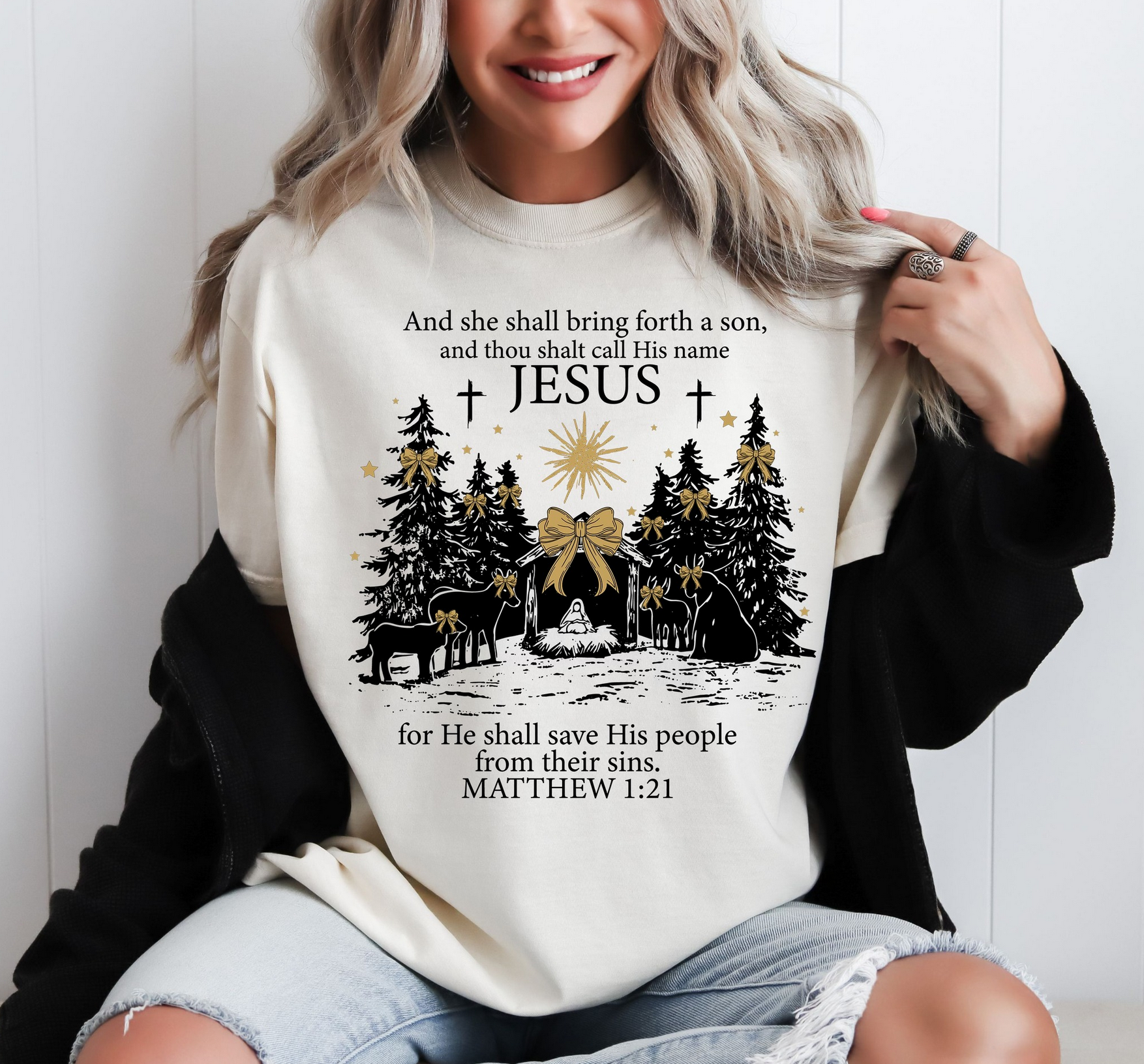 Cream sweatshirt with nativity scene, trees, star, and Matthew 1:21 Bible verse with Jesus’ name highlighted.