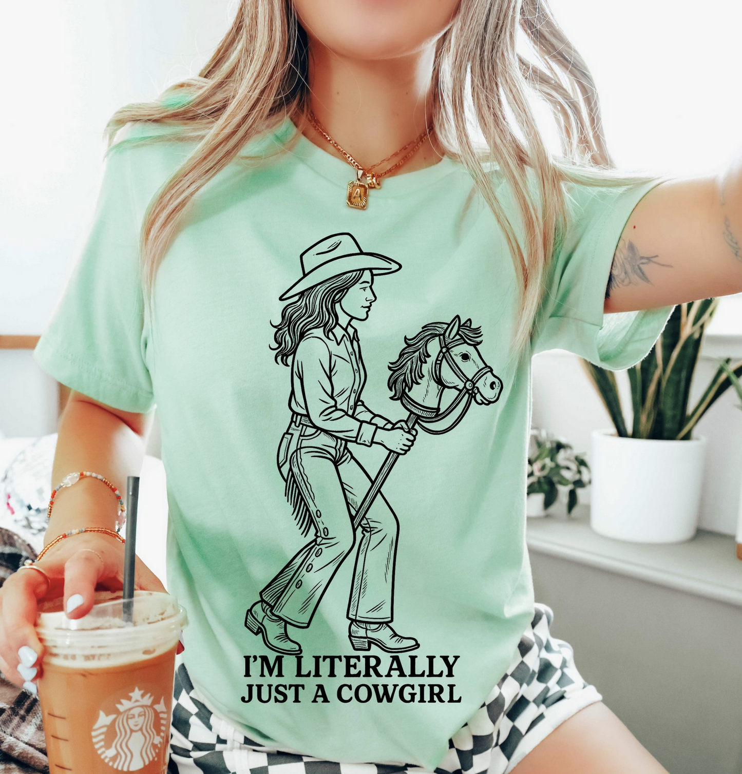 Mint green western graphic tee with cowgirl illustration and text “I’m Literally Just a Cowgirl” – $15 country t-shirt