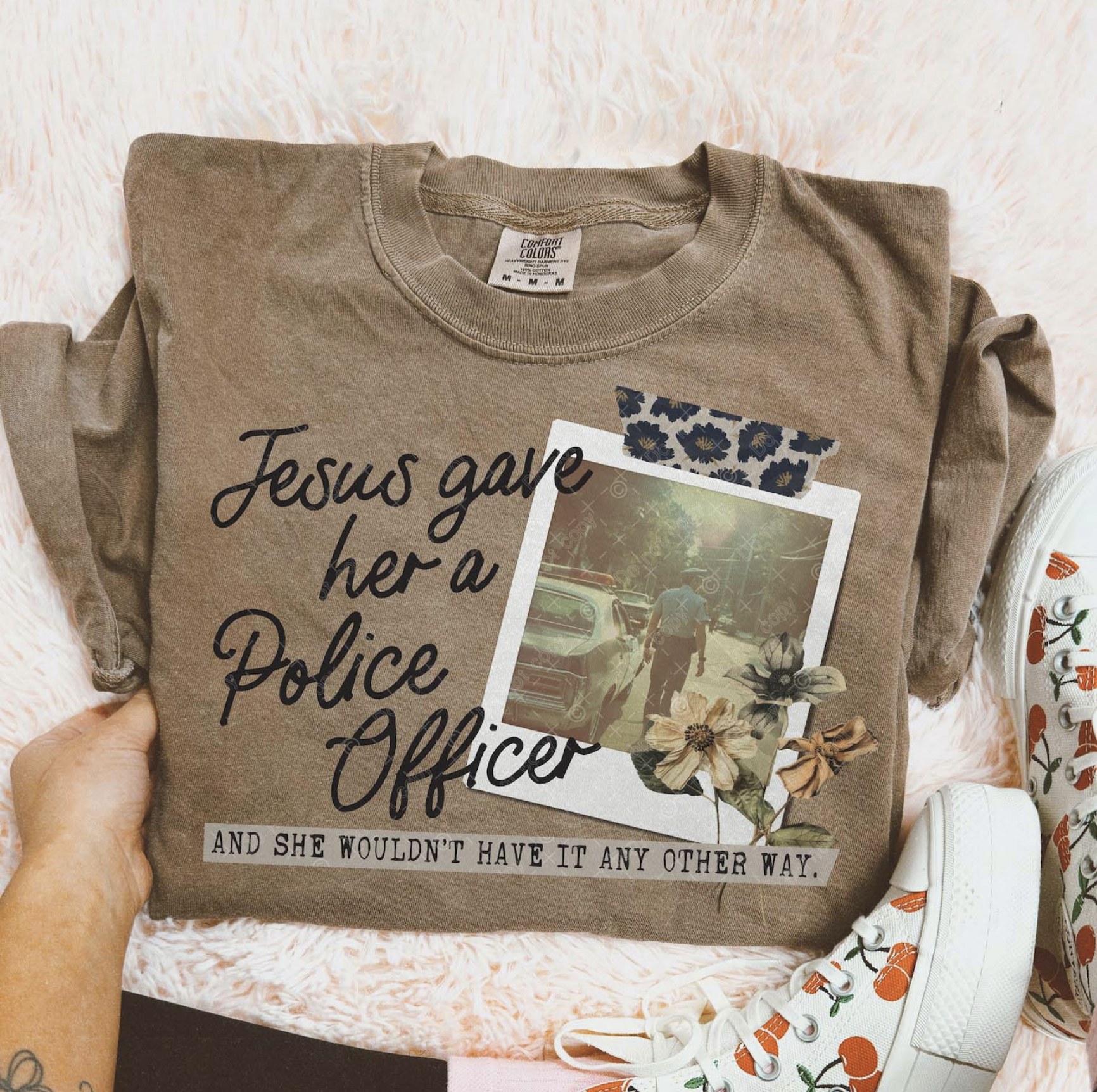 Brown Comfort Colors tee with Christian message “Jesus gave her a police officer” with floral photo design.

Close-up of faith-based police wife graphic on t-shirt.