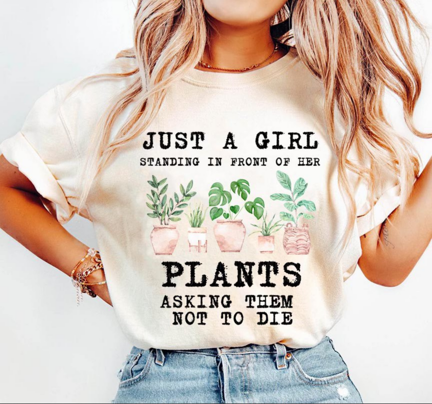 Beige t-shirt with text “Just a girl standing in front of her plants asking them not to die” with illustrated houseplants