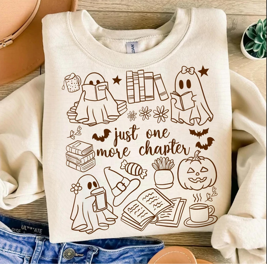 Cream crewneck sweatshirt with ghosts reading books, stacks of novels, pumpkins, and the phrase “Just One More Chapter.”