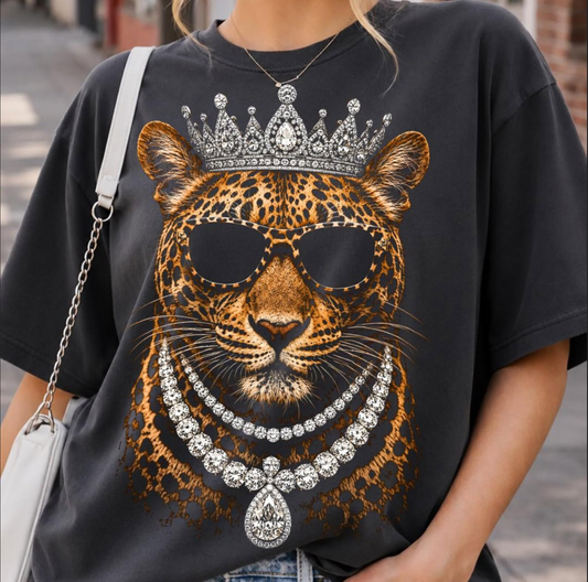 Model wearing a black graphic T-shirt featuring a crowned leopard in sunglasses with printed diamond-style necklaces and jeweled details.
