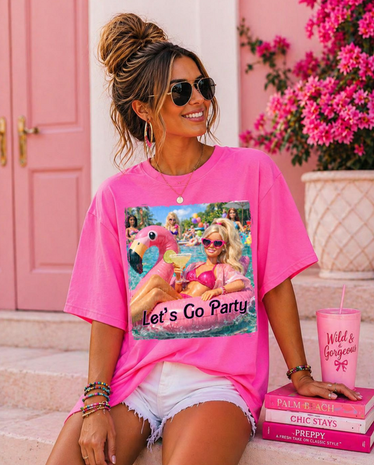 Bright pink graphic t-shirt featuring pool party flamingo float design with Let’s Go Party text for summer boutique fashion