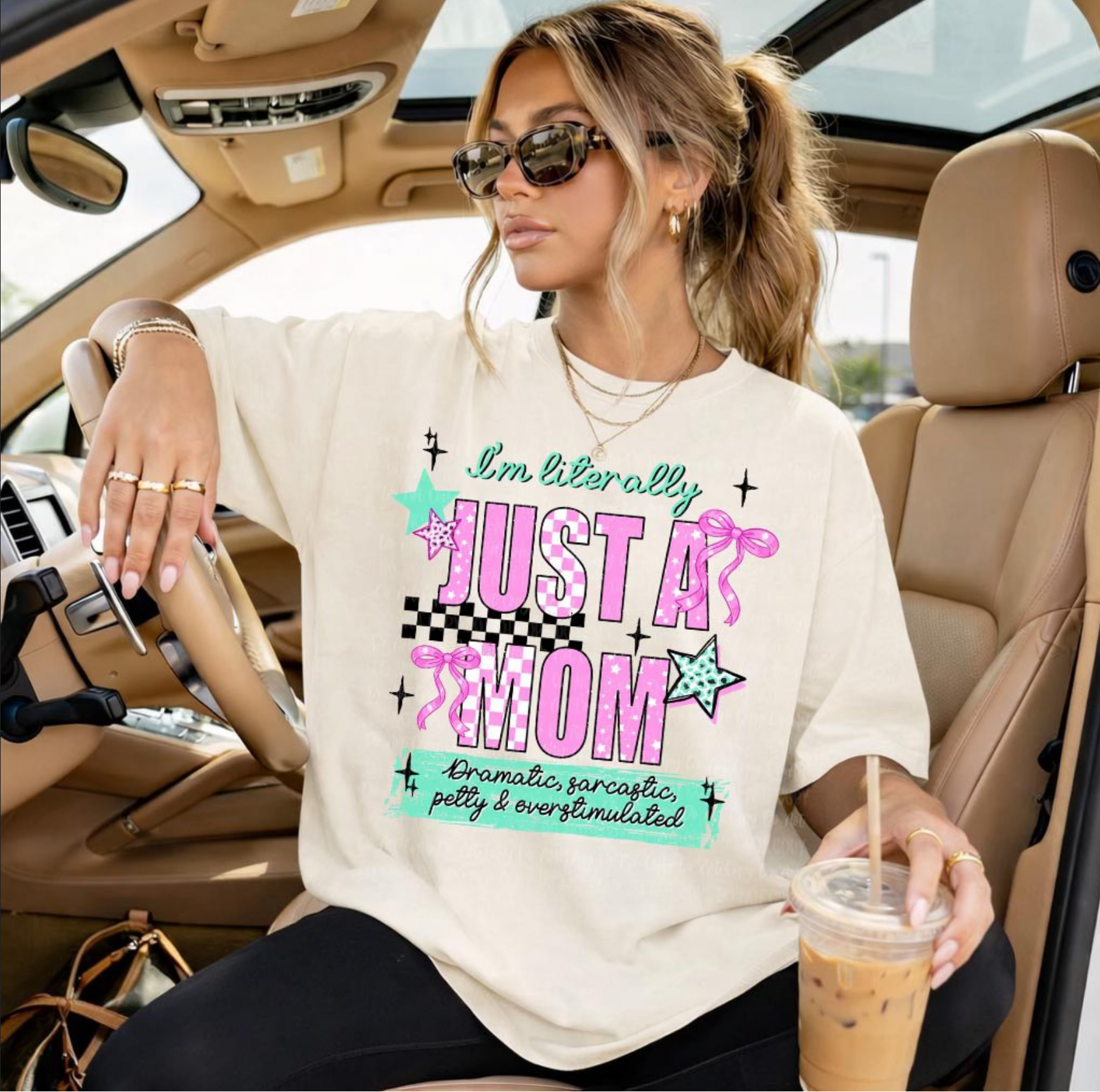 Cream t-shirt with colorful text “I’m literally just a mom” with playful graphic elements worn by woman holding iced coffee
