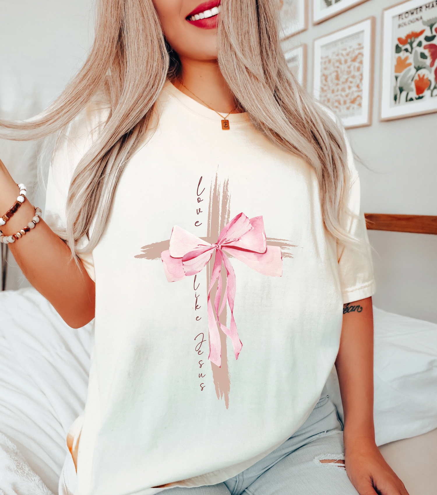 Cream graphic t-shirt featuring a cross design with pink bow and faith-inspired lettering
