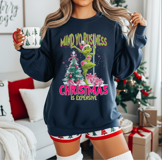 Woman wearing “Mind Yo Business Christmas Is Expensive” navy sweatshirt

Funny holiday sweatshirt with pink and green festive design

Cozy unisex navy crewneck styled for winter

Humorous Christmas outfit idea for the holidays