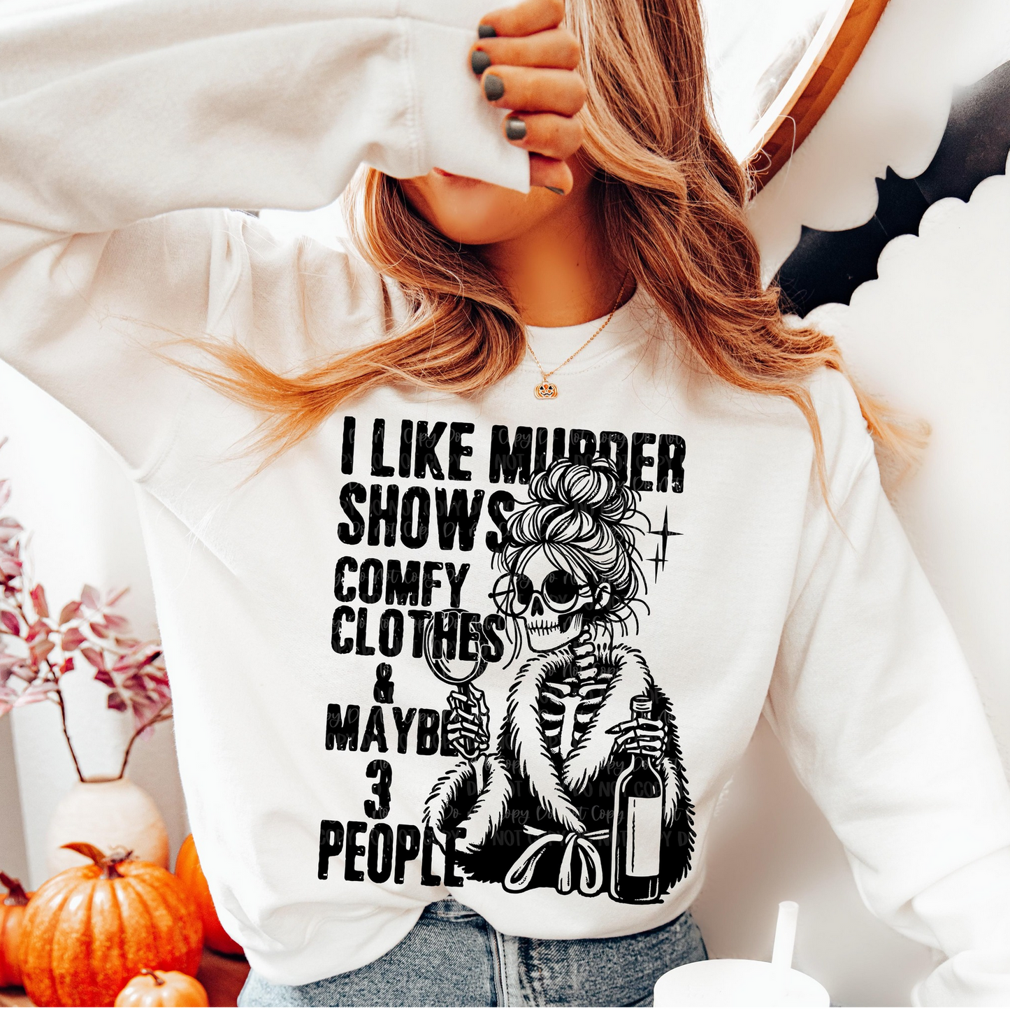 White I Like Murder Shows sweatshirt with black skeleton in robe holding wine and magnifying glass, worn by a woman in a cozy home setting.
