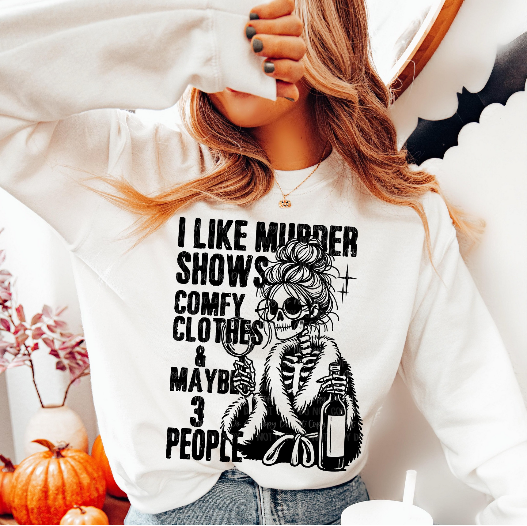 White I Like Murder Shows sweatshirt with black skeleton in robe holding wine and magnifying glass, worn by a woman in a cozy home setting.