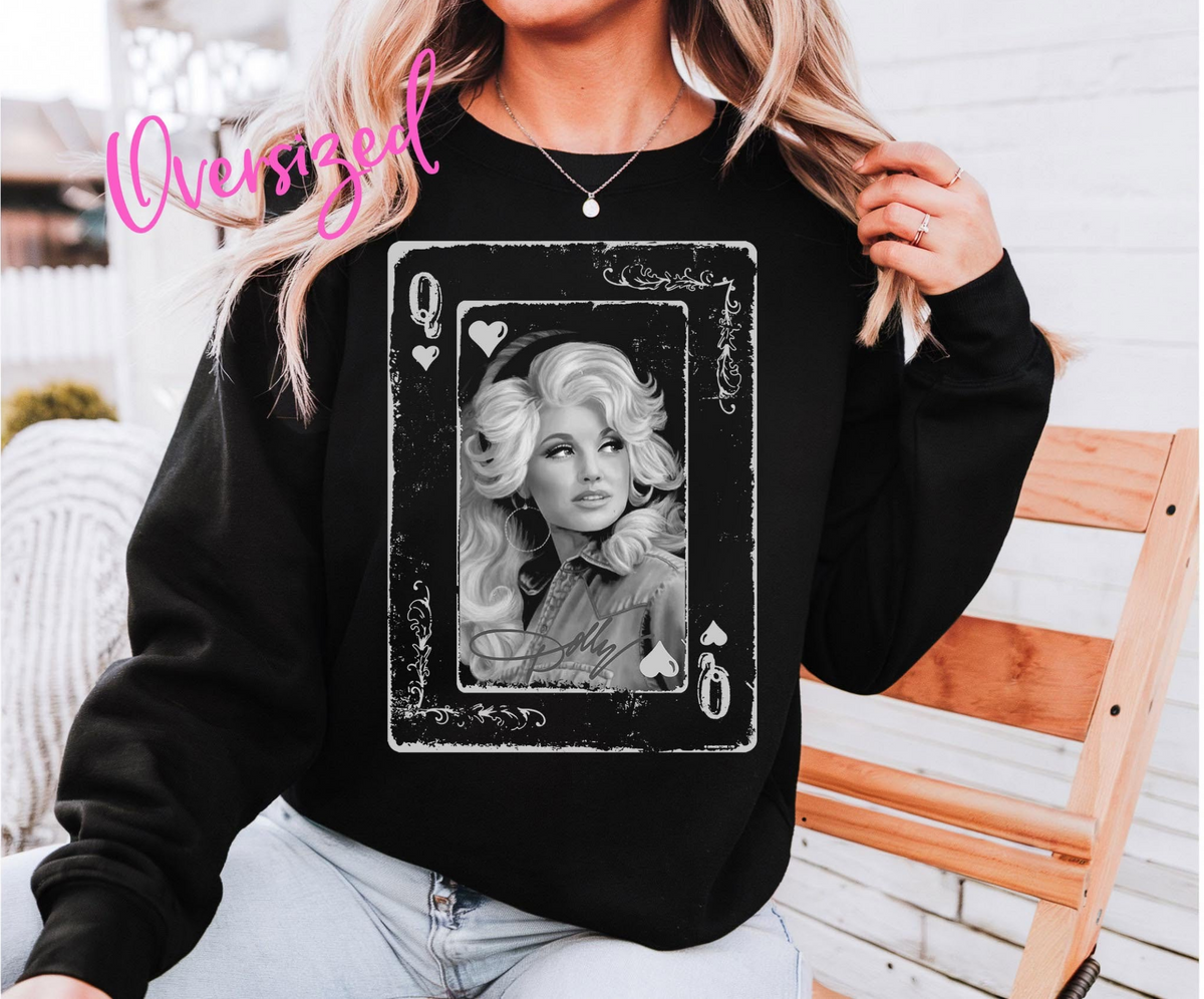 Model wearing a black crewneck sweatshirt featuring a black-and-white Dolly Parton portrait inside a distressed Queen of Hearts playing card.