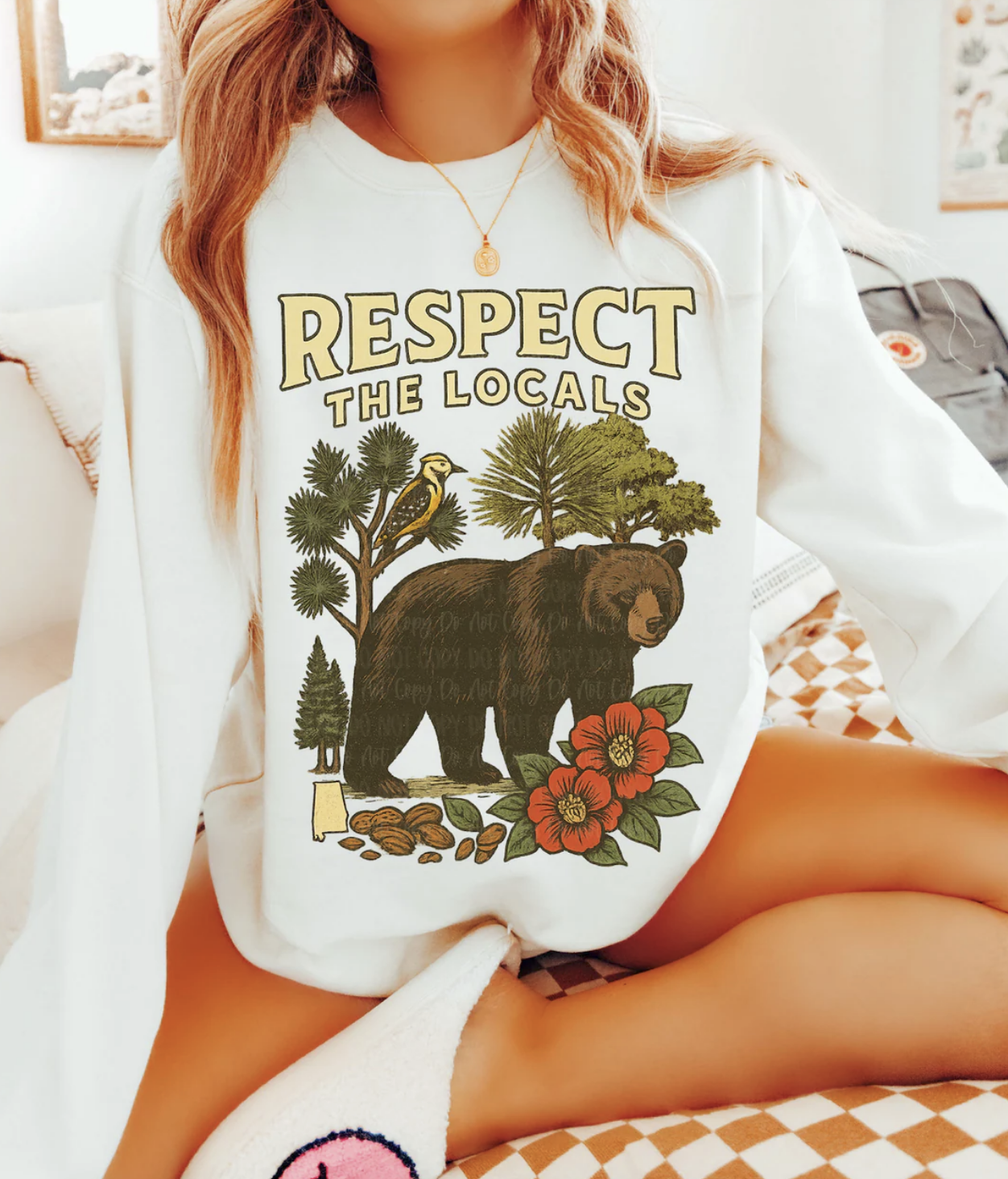 Cream crewneck sweatshirt with “Respect the Locals” text and a graphic of a bear, trees, bird, and flowers.