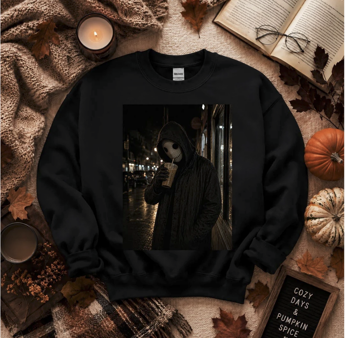 Black crewneck sweatshirt featuring a dark photo-style graphic of a hooded masked figure sipping coffee on a rainy nighttime street.