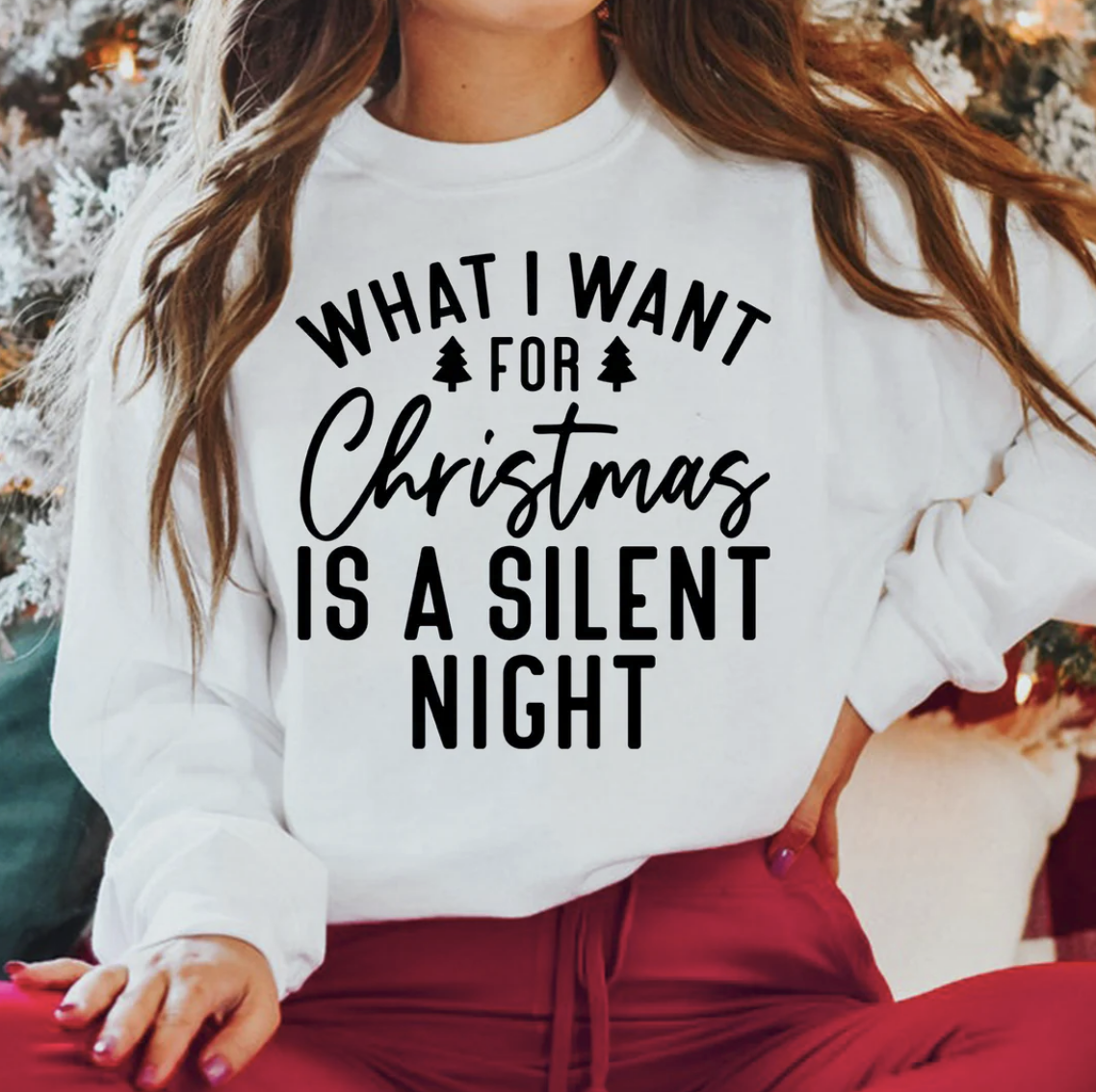 “Woman wearing a white shirt with black text that reads ‘What I Want for Christmas Is a Silent Night.’”