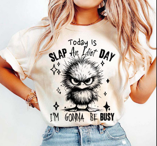 Beige t-shirt with grumpy cartoon bird and text “Today Is Slap an Idiot Day I’m Gonna Be Busy” – funny sarcastic graphic tee
