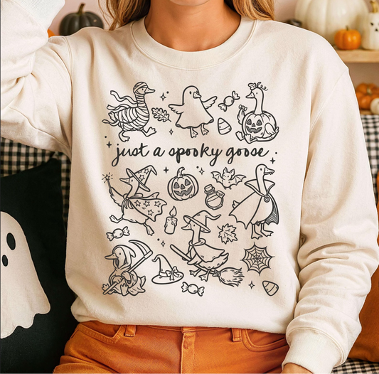 Cream crewneck sweatshirt with hand-drawn geese in Halloween costumes — ghost, pumpkin, mummy, witch — and the phrase “Just a Spooky Goose.”