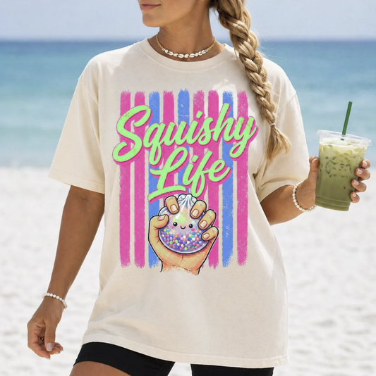 Beige t-shirt with colorful “Squishy Life” text and a hand holding a squishy toy with retro stripes