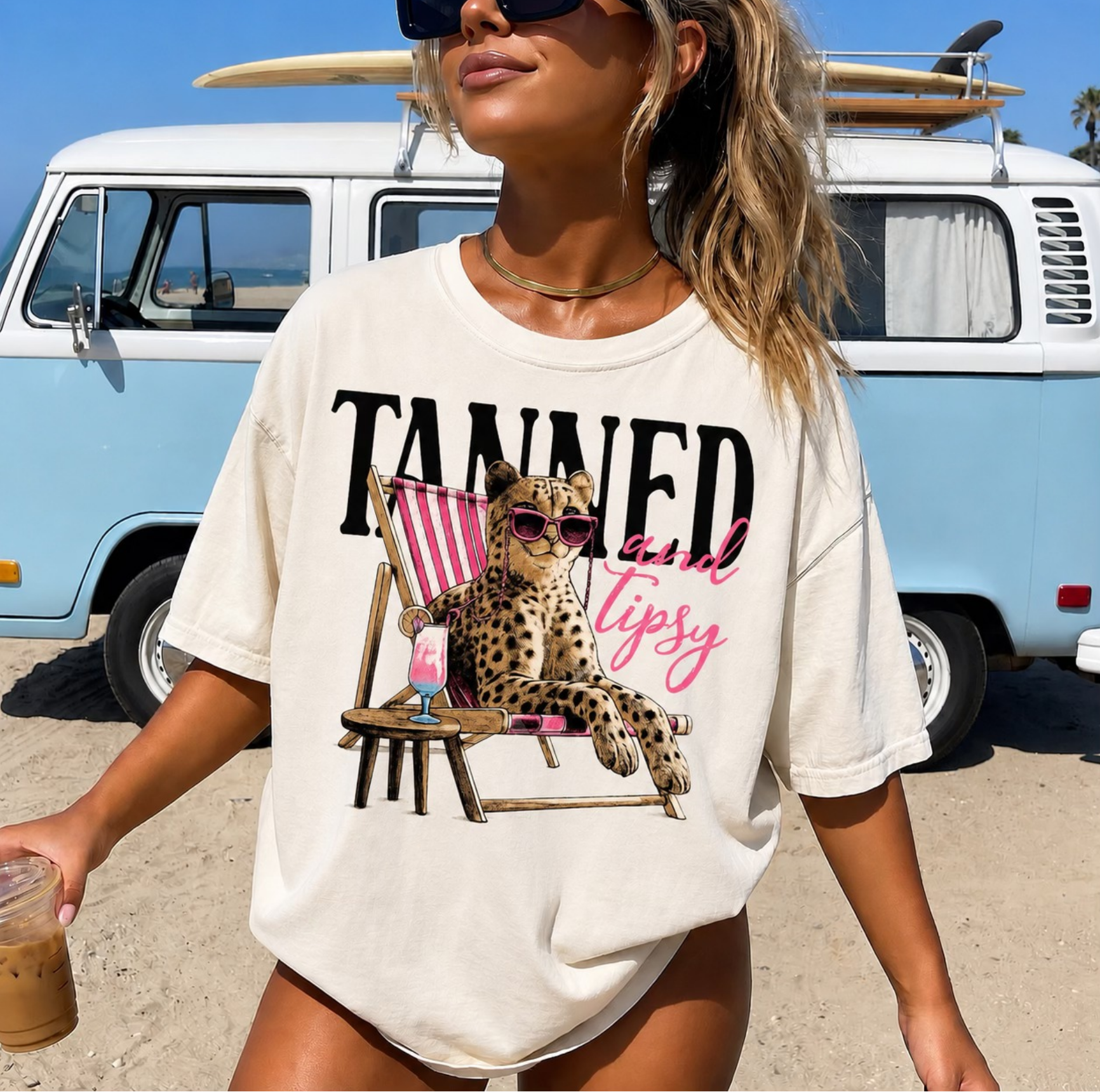Cream t-shirt with cheetah lounging in beach chair with drink and text “tanned and tipsy”