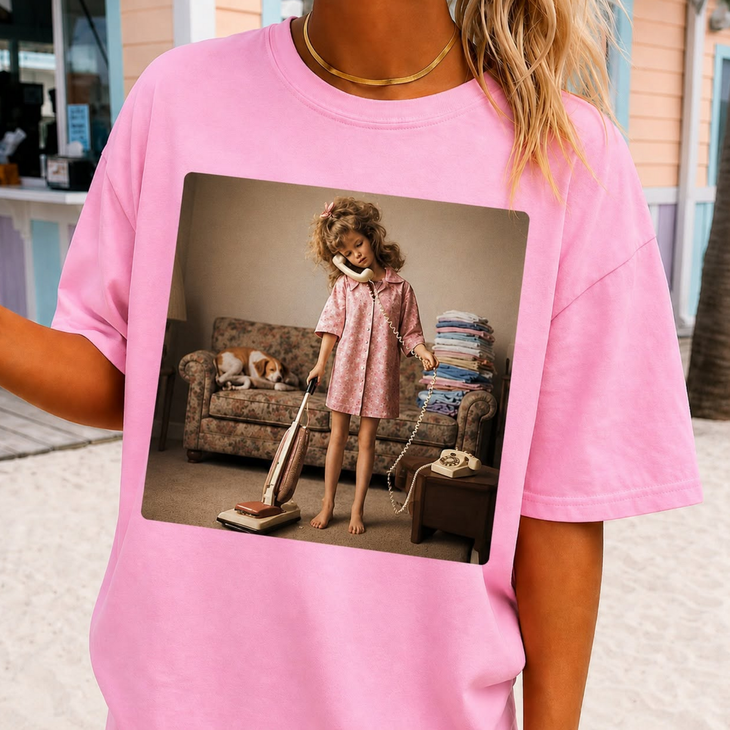 Pink graphic t-shirt featuring a vintage style image of a young girl vacuuming while talking on the phone representing busy mom life.